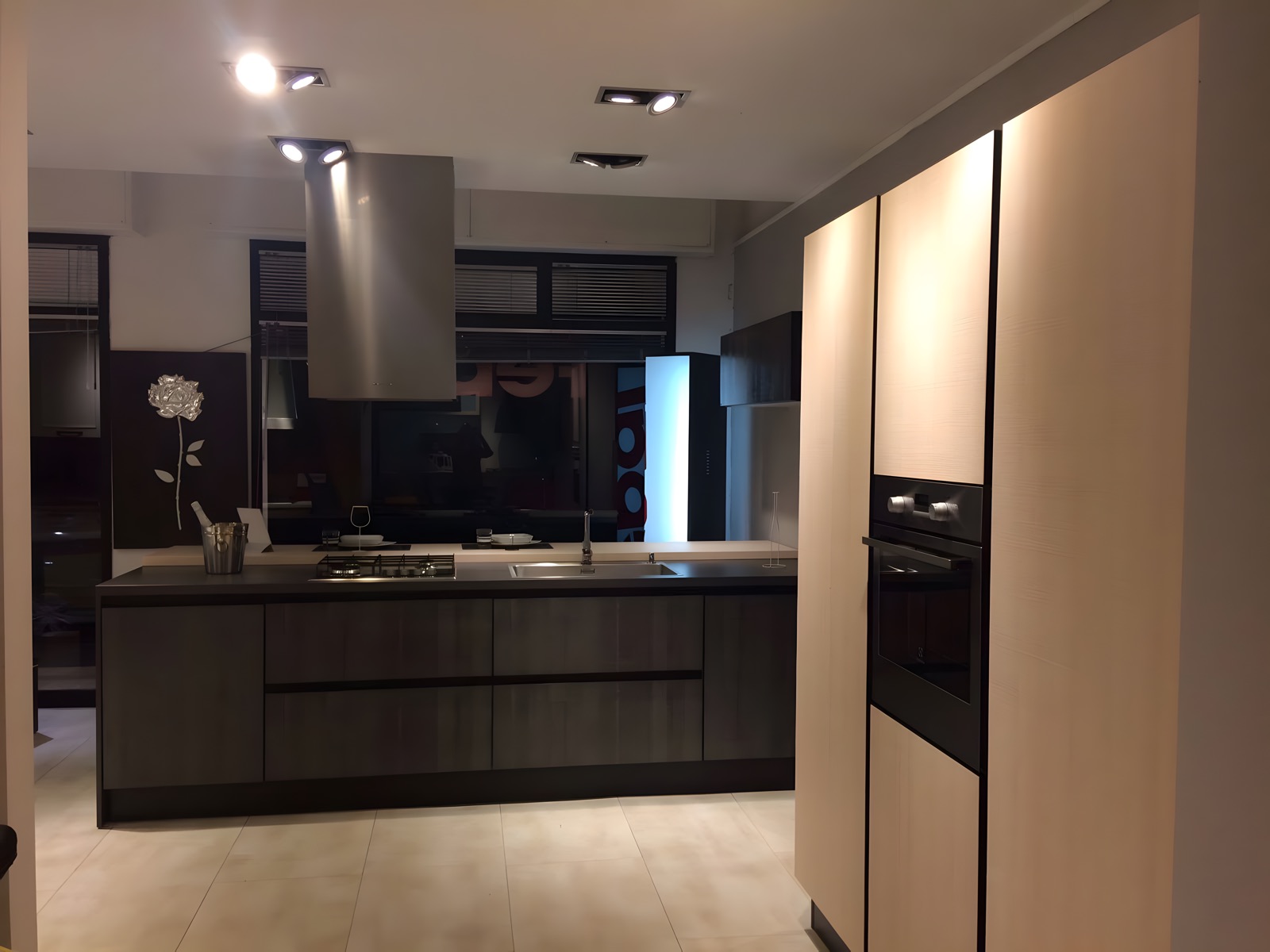 Cucina con isola in essenza scura e colonne in rovere chiaro con forno a incasso